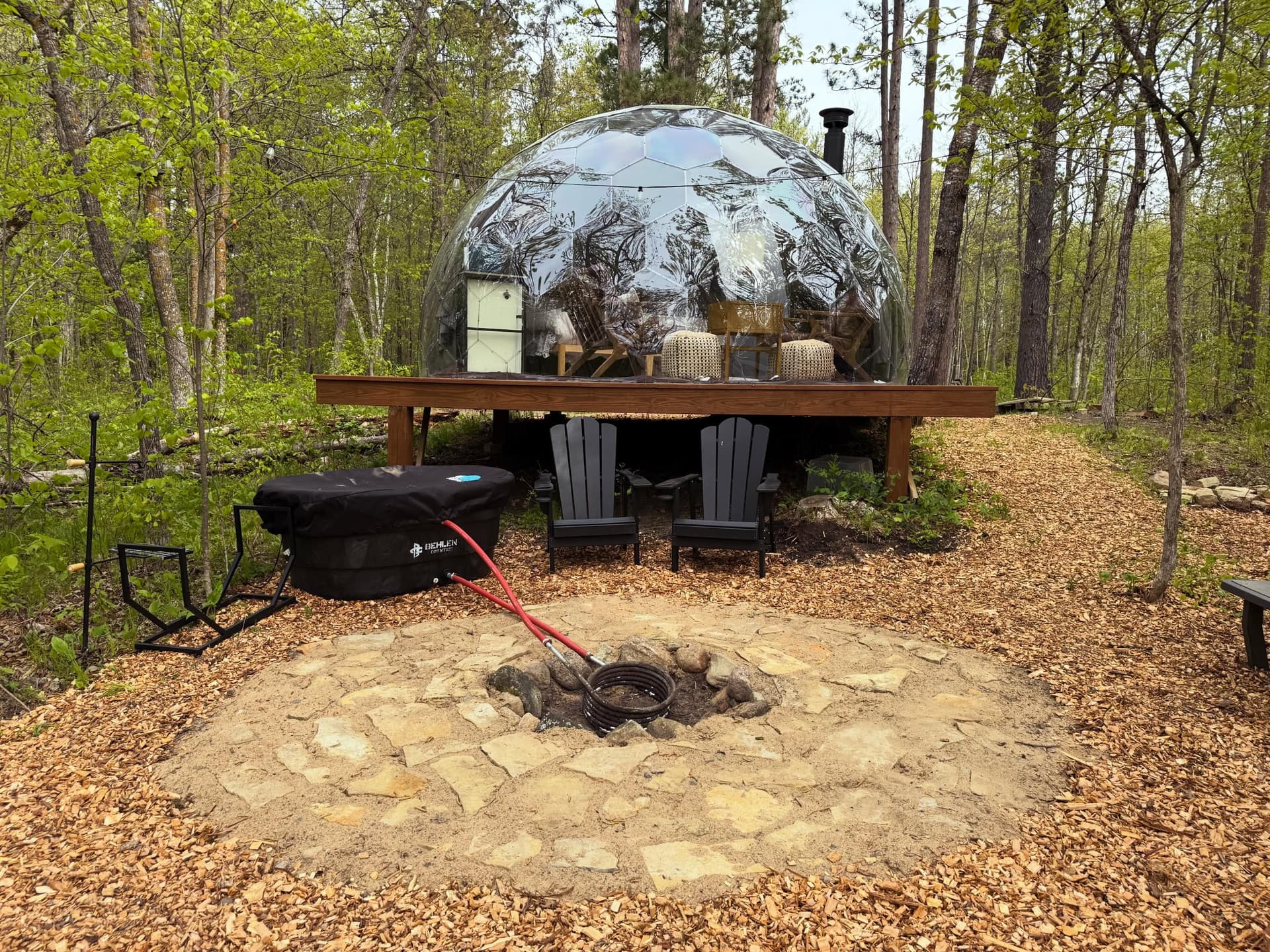Geodesic dome on a raised platform in a wooded clearing