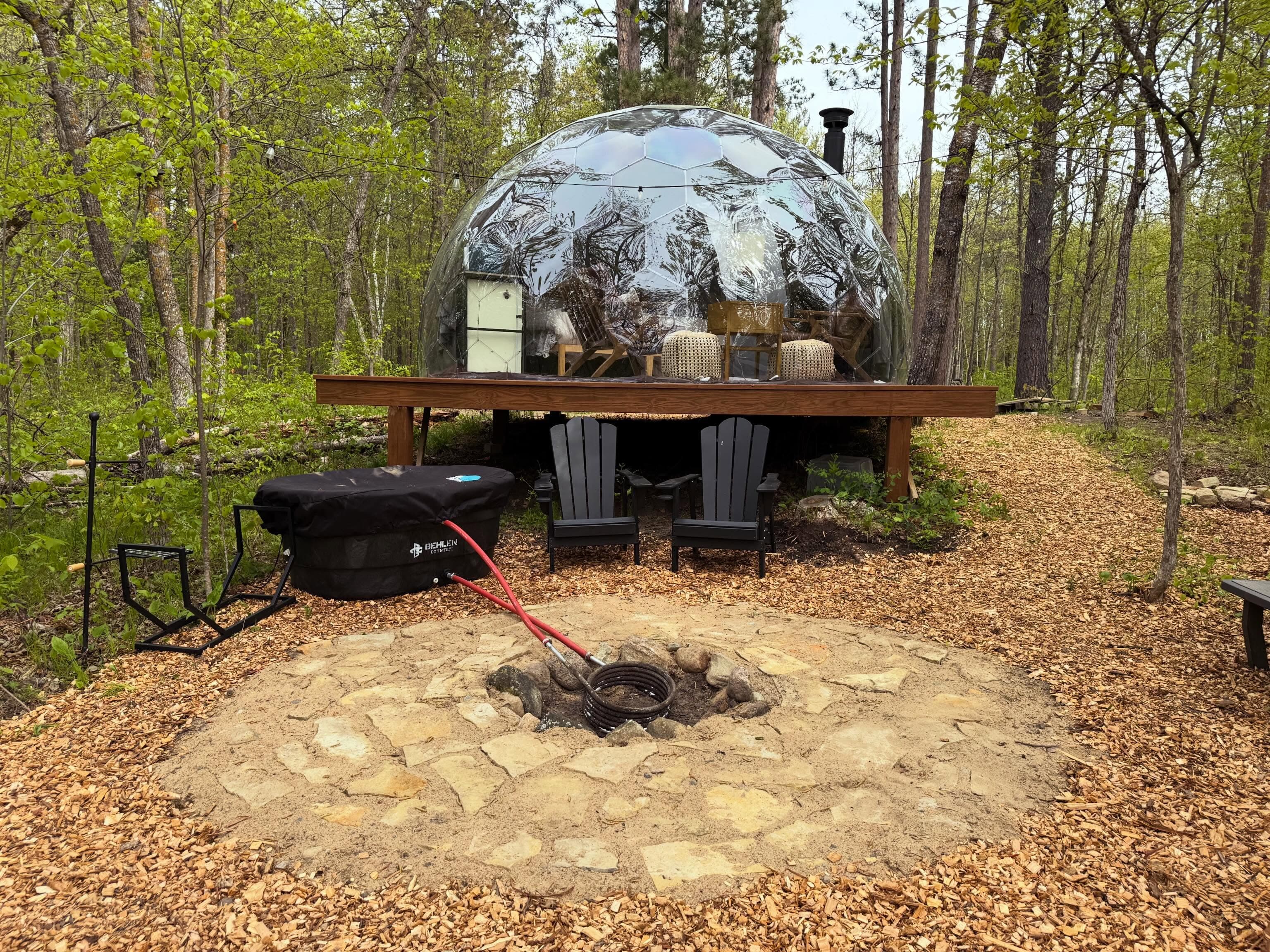 Front view of a geodesic dome glamping structure on a raised wooden platform